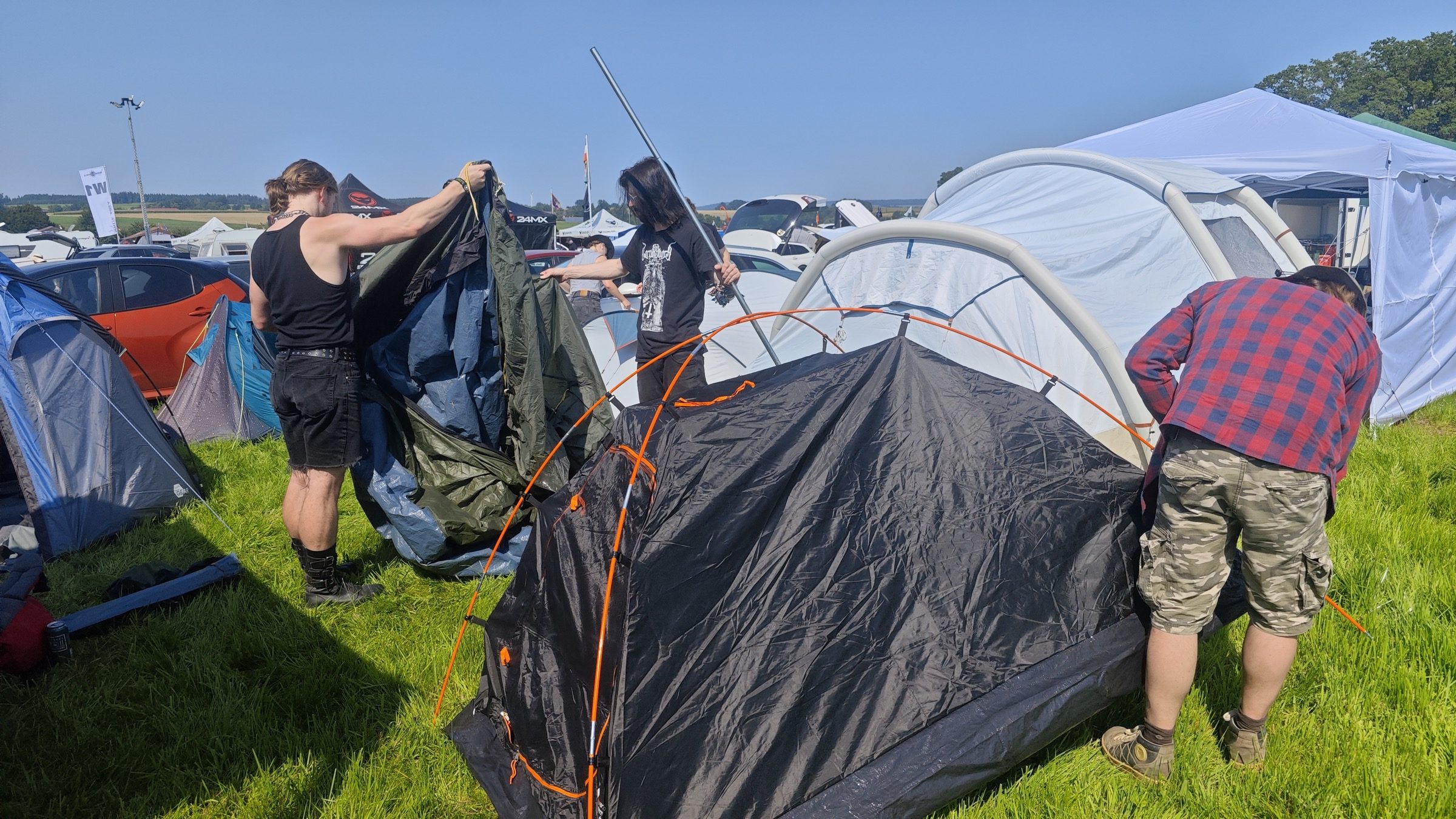Zelte und Camping-Equipment beim Aufbau auf einem Festival-Campingplatz