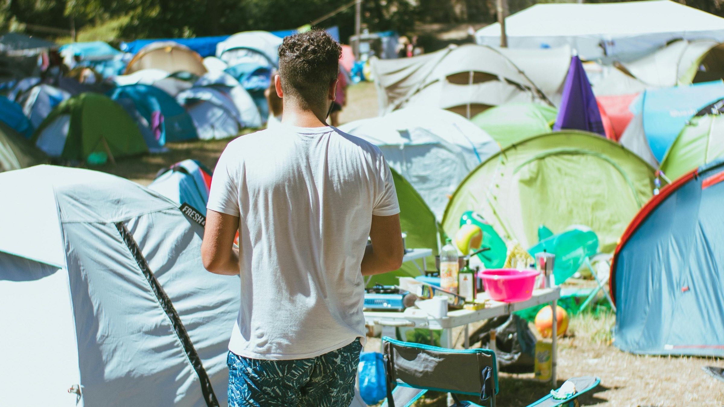 Person läuft durch einen Festival-Campingplatz mit vielen Zelten