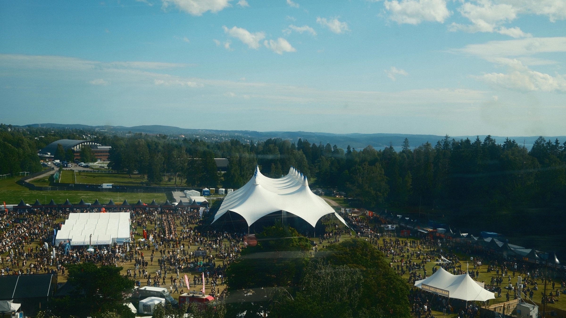 Festivalgelände von oben mit mehreren Bühnenbereichen und Publikum