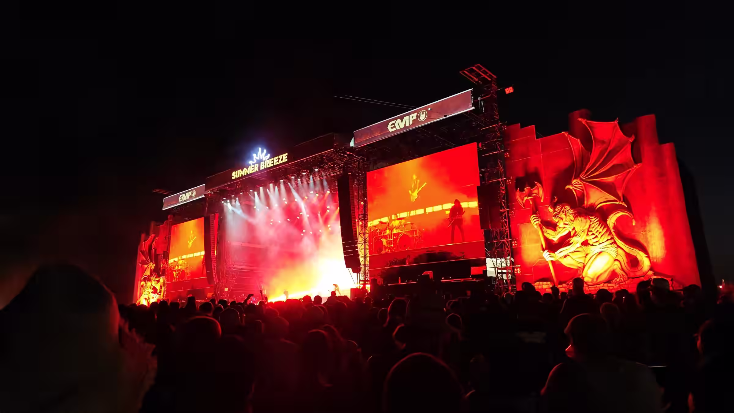 Rot beleuchtete Metal-Festivalbühne vor einer großen Crowd